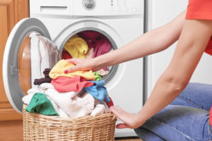 Preparing the wash cycle. Washing machine, hands and clothes.